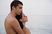Young couple embracing on beach\n