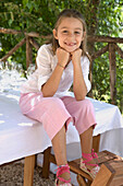 Porträt eines jungen Mädchens, das am Tisch sitzt