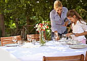 Mother and daughter setting table\n