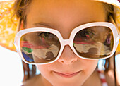 Close up of young girl with oversized sunglasses\n