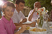Family having pasta meal with smiling young boy in the foreground\n
