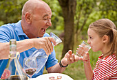 Granddad and granddaughter drinking water\n