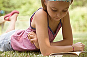 Girl lying on stomach reading book\n