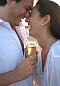 Couple on Beach Laughing and Toasting with Champagne\n