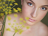 Young beautiful woman lost in thought with yellow flower\n