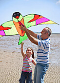 Portrait of father and daughter flying a kite\n