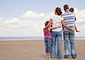 Rückenansicht einer jungen Familie am Strand