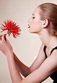 Portrait of young beautiful woman holding red dahlia\n