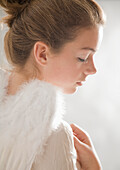 Close up of young woman with white feather wings\n