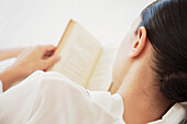 Rückenansicht einer Frau beim Lesen eines Buches