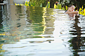 Portrait of young woman in an exotic swimming pool resting\n