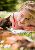Young woman lying on the grass caressing a cat\n