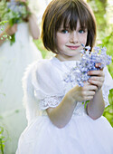 Portrait of a young girl in a fairy costume holding flowers\n