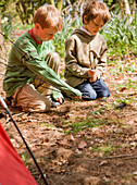 Portrait of two boys building a tent\n