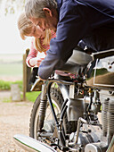 Junges Mädchen hilft Großvater bei der Reparatur eines Motorrads