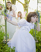 Portrait of a young girl in a fairy costume sitting on a swing\n