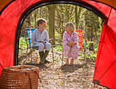 Portrait of boy and girl sitting outside tent entrance\n