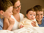 Porträt einer Frau im Bett mit ihren Kindern und ihrem Neugeborenen