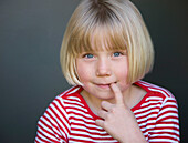Portrait of a young girl with finger in her mouth\n
