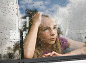 Portrait of a young girl looking out of a car window\n
