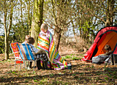 Young girl wrapped in a blanket interacting with friends at campsite\n