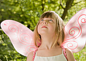 Girl in a pink fairy costume looking up\n