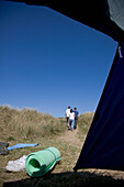 Back of three people walking with tent opening\n