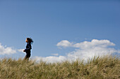 Young woman running through sand dunes\n