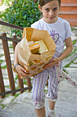 Young girl walking up stairs carrying a brown paper bag\n