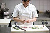 Woman chef peeling garlic with a knife\n