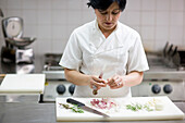 Woman chef peeling garlic with a knife\n