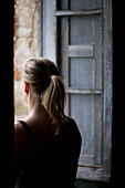 Back view of a woman looking out of a window\n