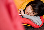 Nahaufnahme eines schlafenden Mädchens im Teenageralter, dessen Kopf aus dem Zelteingang kommt