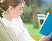 Teenaged girl sitting and reading a book\n
