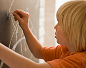 Young boy writing on a blackboard\n