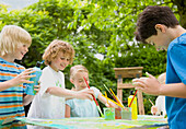 Children painting and smiling in Garden\n