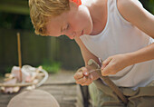 Junge knüpft einen Knoten mit einer Schnur um einen Holzstab