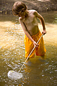 Junge beim Fischen im Fluss mit Fischernetz