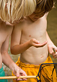 Two young boys inspecting the content of a fishing net\n