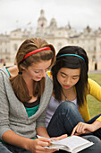 Zwei Mädchen im Teenageralter lesen ein Buch vor der Londoner Horse Guards Parade