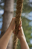 Close up of a woman hands hanging from a rope\n