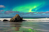 Wellen brechen an Felsen unter einem hellen Himmel mit Aurora Borealis (Nordlicht), Skagsanden Strand, Ramberg, Lofoten Inseln, Nordland, Norwegen, Skandinavien, Europa