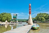 Die Forks Historic Port und die Forks Historic Railway Bridge, erbaut 1913 und in den 1960er Jahren von der Eisenbahn auf Fußgängerverkehr umgestellt, über den Assiniboine River, Winnipeg, Manitoba, Kanada, Nordamerika