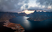 Sturmwolken bei Sonnenuntergang über majestätischen Bergen entlang eines Fjords, Luftaufnahme, Reine Bucht, Lofoten Inseln, Nordland, Norwegen, Skandinavien, Europa