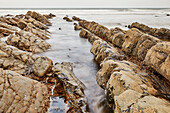 A rising tide brings the Atlantic around and over shoreline rocks at Welcombe Mouth, a remote cove near Hartland, on the Atlantic coast of Devon, England, United Kingdom, Europe\n