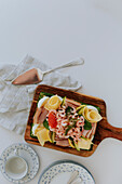 Swedish sandwich cake with shrimps, cheese, ham and eggs on wooden board at table\n