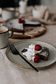 Portion Schokoladenkuchen mit Sahne und Himbeeren auf einem Teller