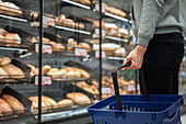 Man with shopping basket in bakery section of supermarket\n