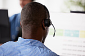 Rear view of man using headset while sitting in office\n