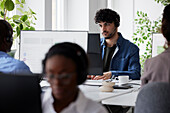 Young man using headset while sitting in office\n